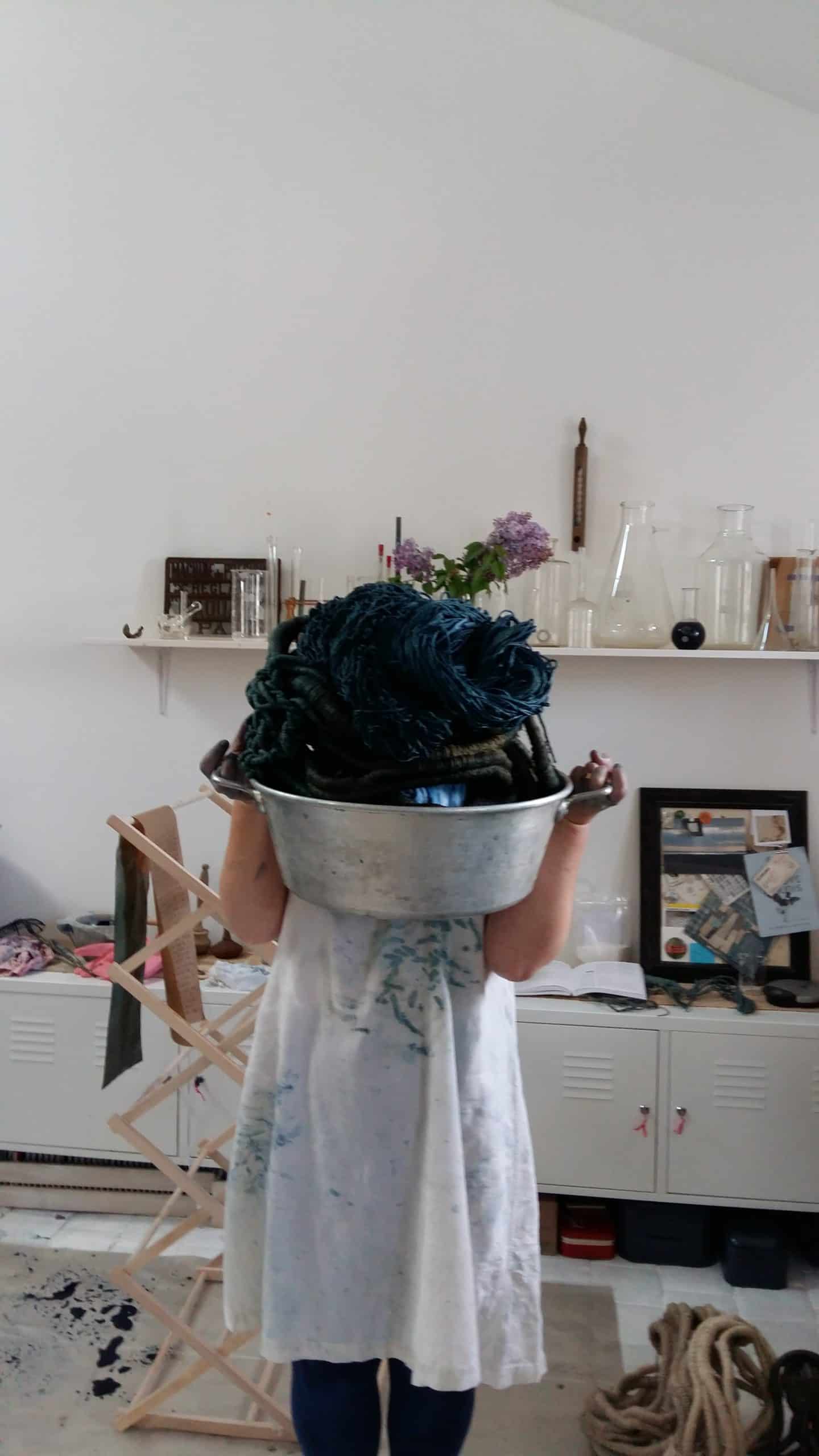 Picture of artist Aude Franjou carrying a cauldron of freshly dyed linen string.