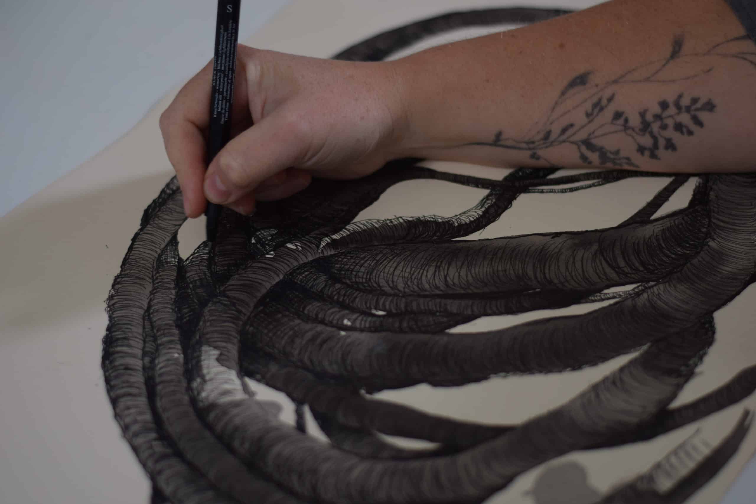 Artist Aude Franjou is drawing a black sculpture on a sheet of paper