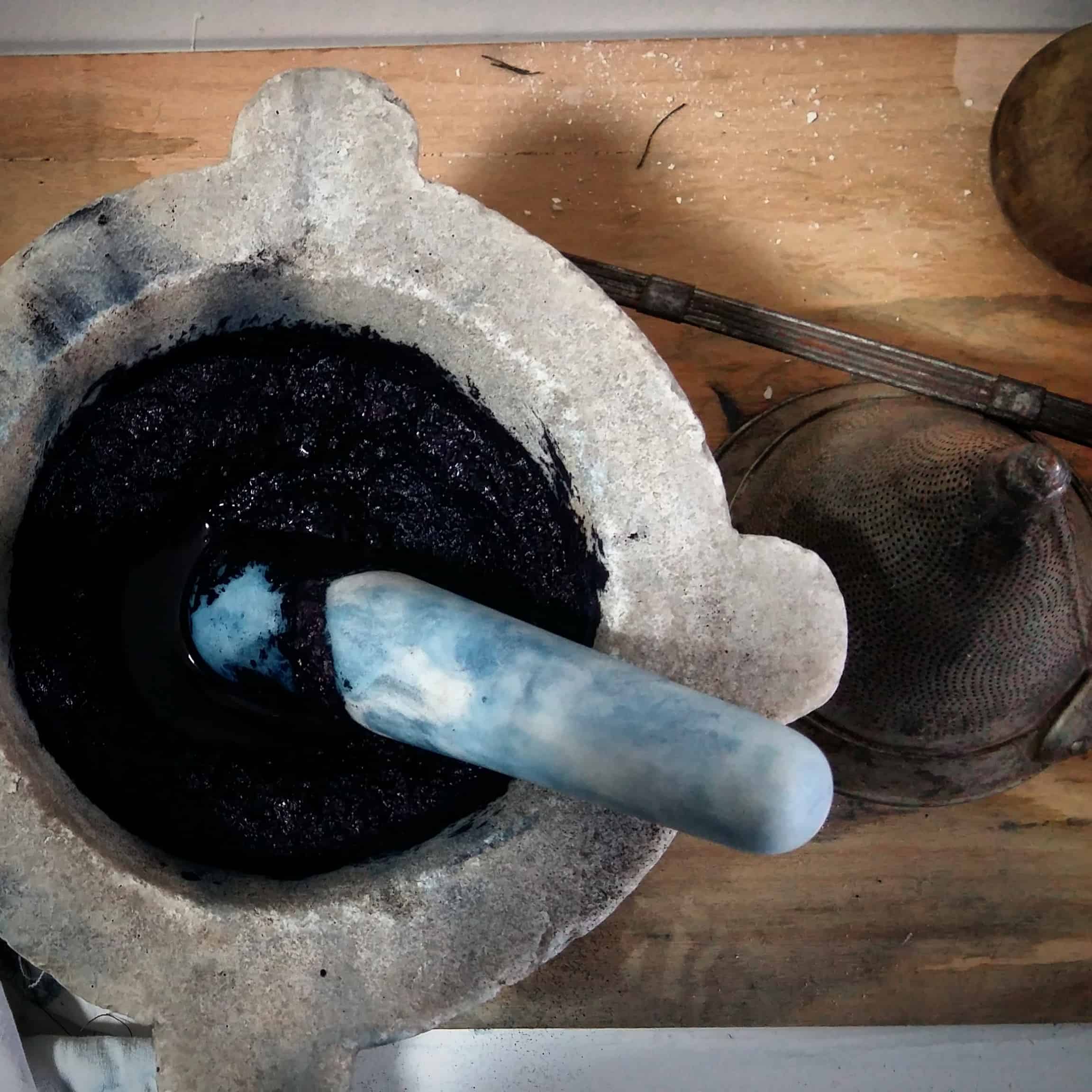 Picture of a pestle and mortar containing powdered indigo dye.