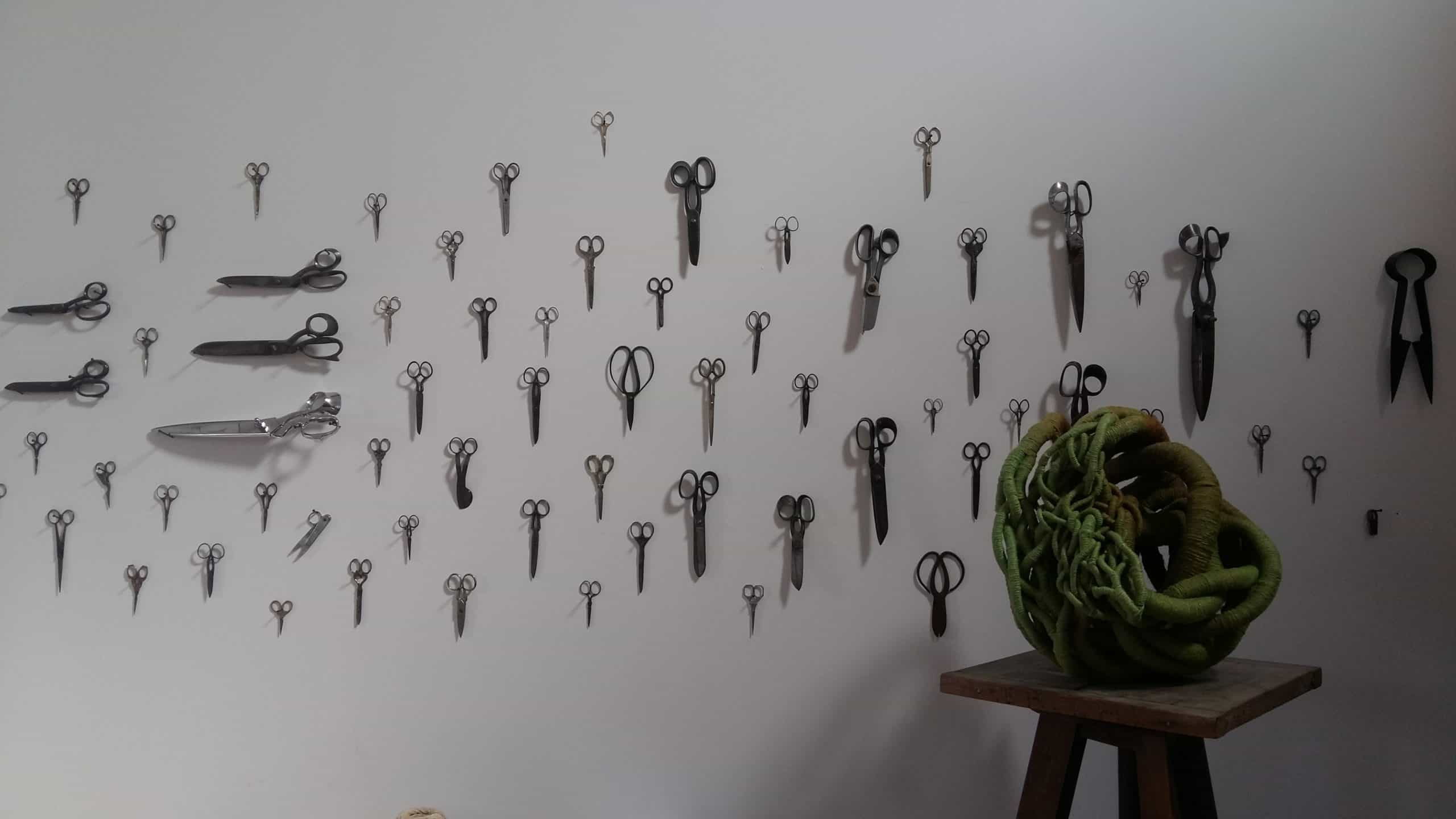 Picture of a sculpture and a collection of scissors on a wall in artist Aude Franjou's workshop.