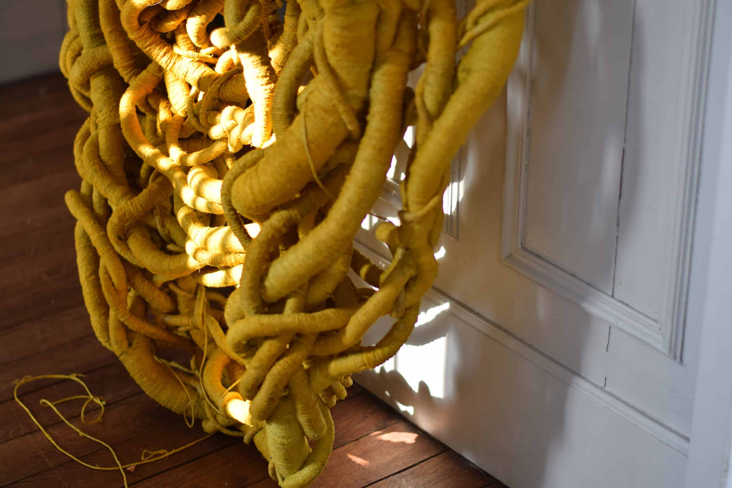 Yellow sculpture on wooden floor in afternoon sun by Aude Franjou