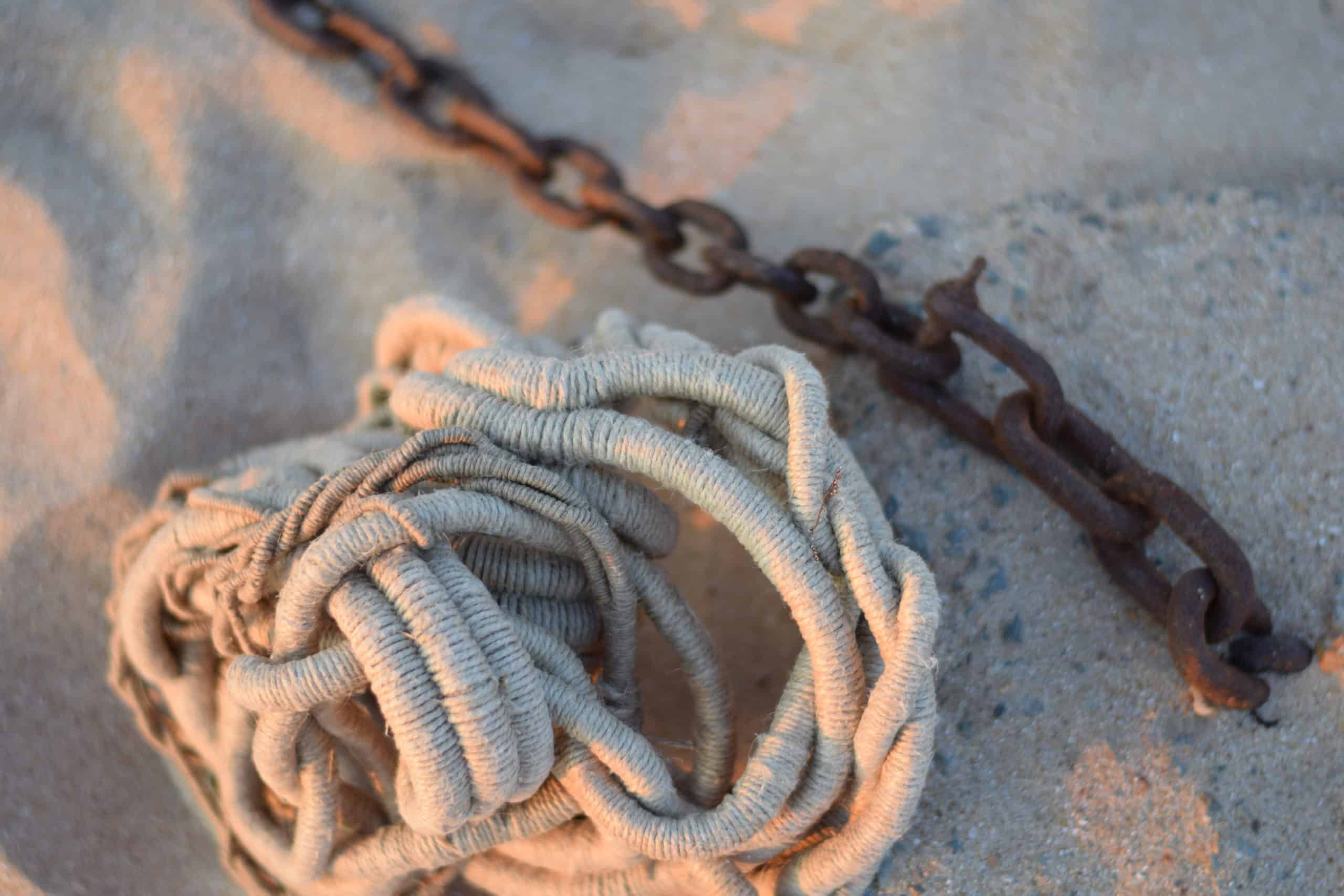 Undyed sculpture by Aude Franjou on a beach next to an anchoring chain