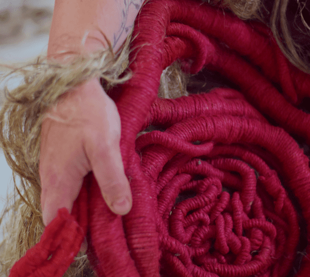 Red linen sculpture and raw linen fibres held in sculptor Aude Franjou's hand