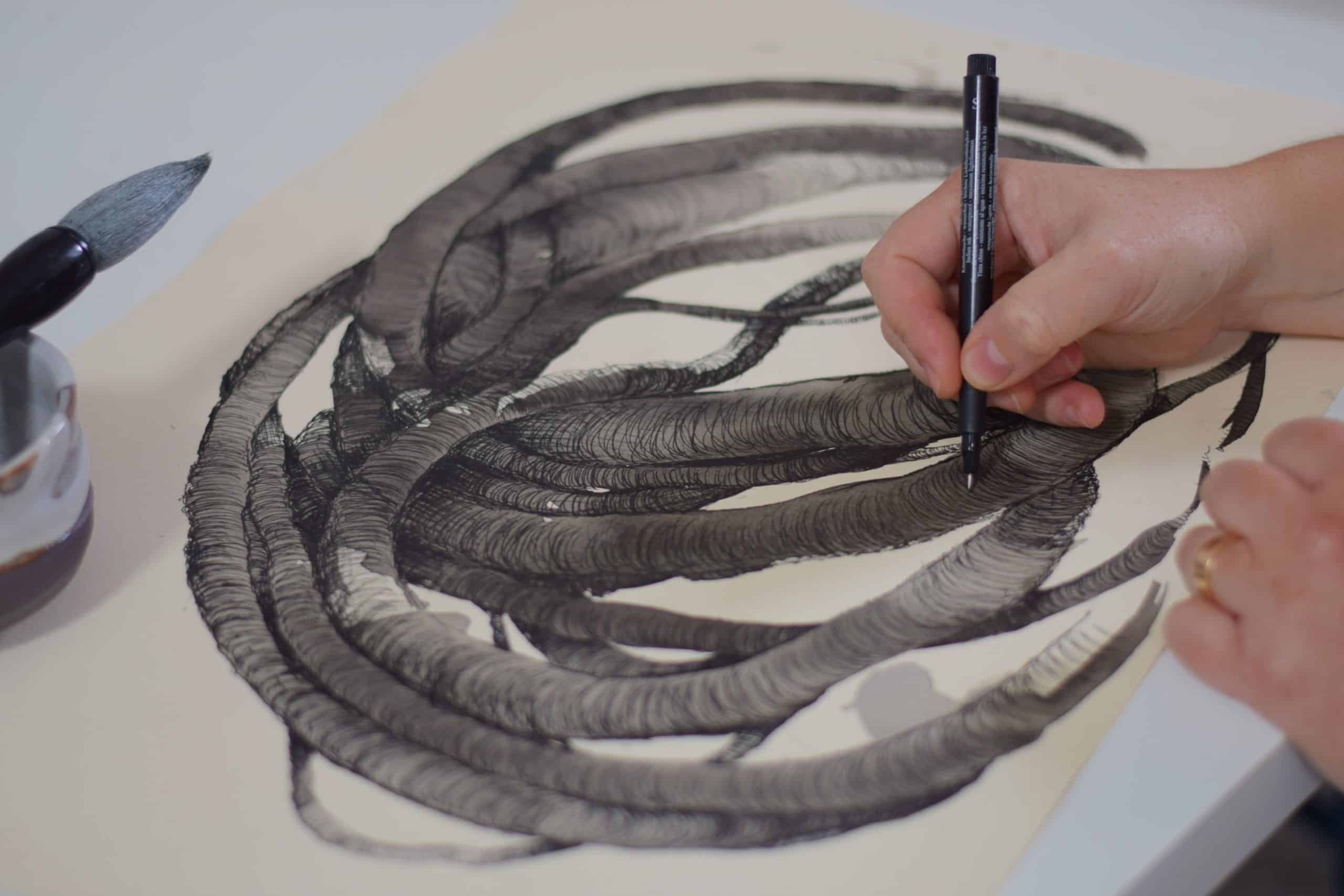 Aude Franjou drawing and painting on a sheet of paper