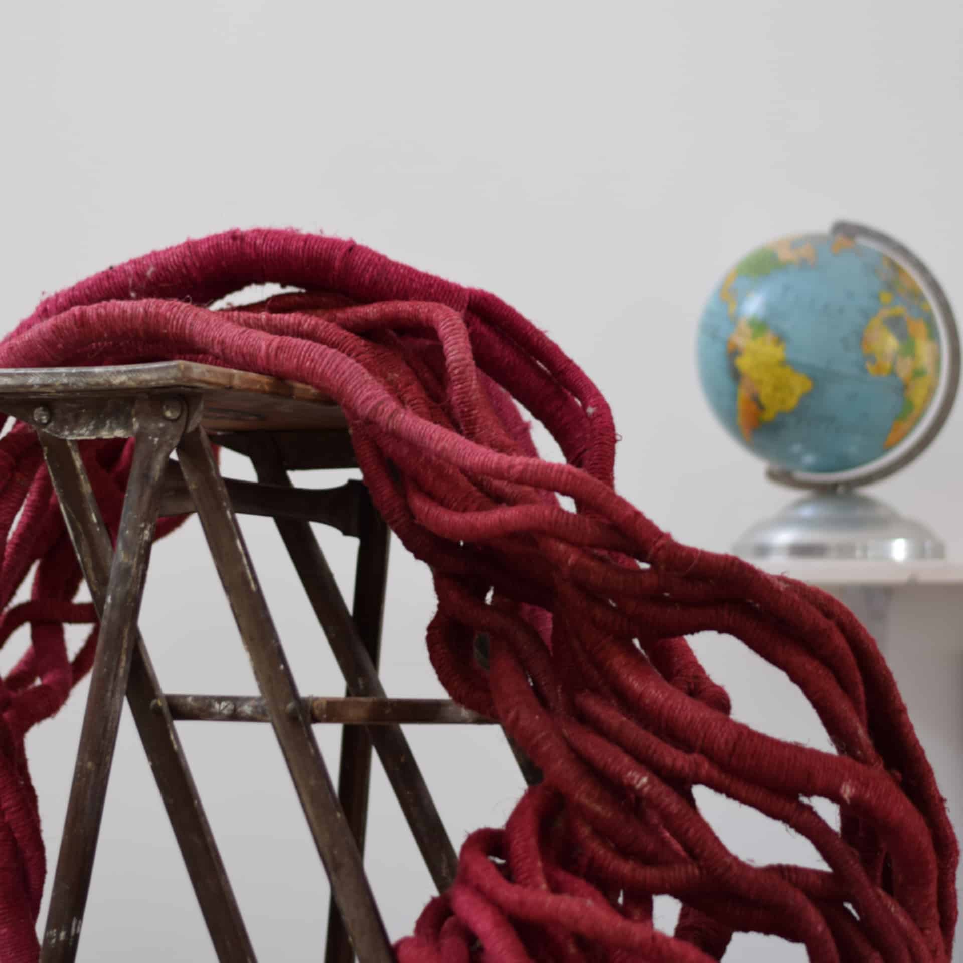 Red linen hot-dyed sculpture on stepladder and globe by Aude Franjou